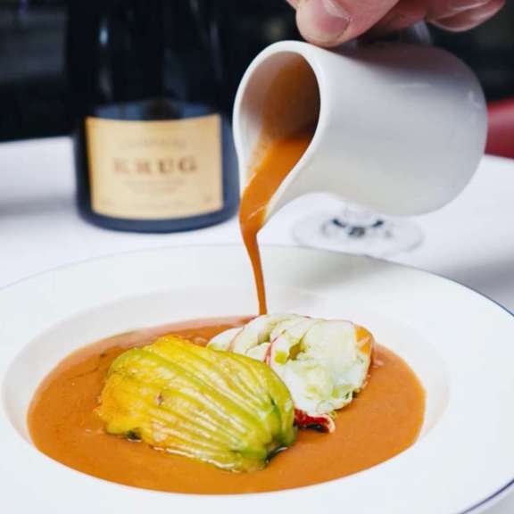 Rich bisque being poured over seafood at Bentley’s Oyster Bar, a top seafood restaurant in Mayfair.