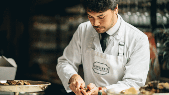 man shucking an oyster at Bentley's Oyster Bar & Grill seafood restaurant in Mayfair, London